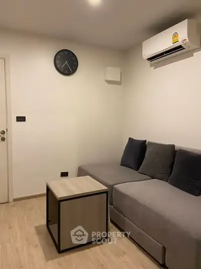 Modern living room with sleek gray sofa and wall-mounted air conditioner.