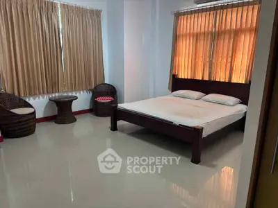 Spacious bedroom with elegant wicker chairs and large windows for natural light.