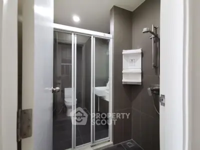 Modern bathroom with glass shower and sleek fixtures in contemporary apartment.