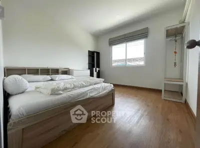 Spacious bedroom with modern wooden flooring and ample natural light