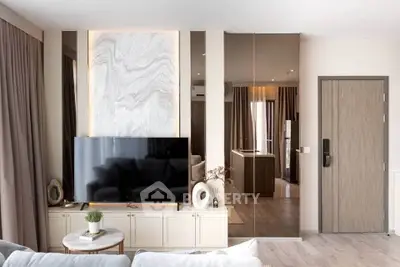 Modern living room with stylish decor, large TV, and elegant marble accent wall.