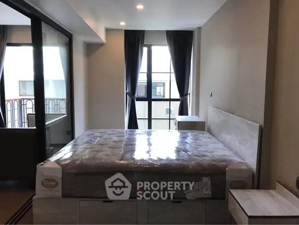 Modern bedroom with large window and balcony access in a stylish apartment.