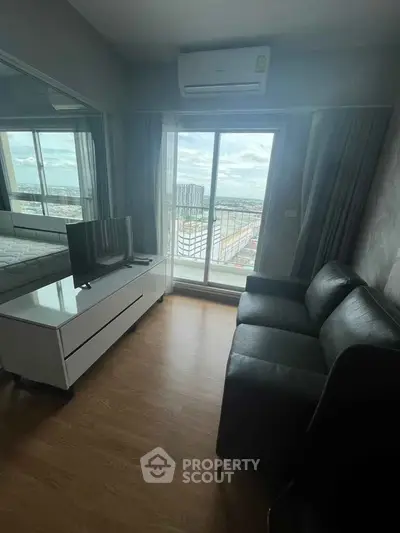 Modern living room with balcony view, featuring sleek black sofa and wall-mounted TV, perfect for urban living.