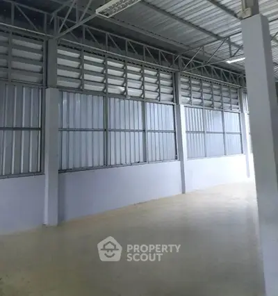 Spacious industrial warehouse with high ceilings and metal walls, perfect for storage or manufacturing.