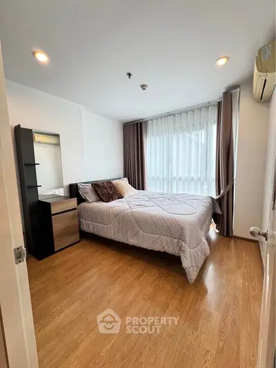 Cozy bedroom with wooden flooring and large window, featuring a comfortable bed and stylish decor.
