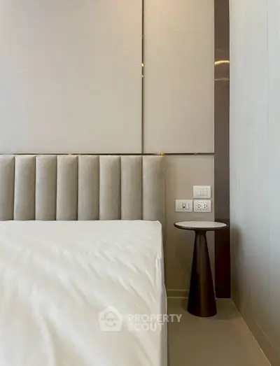 Modern bedroom corner with stylish side table and elegant wall paneling.