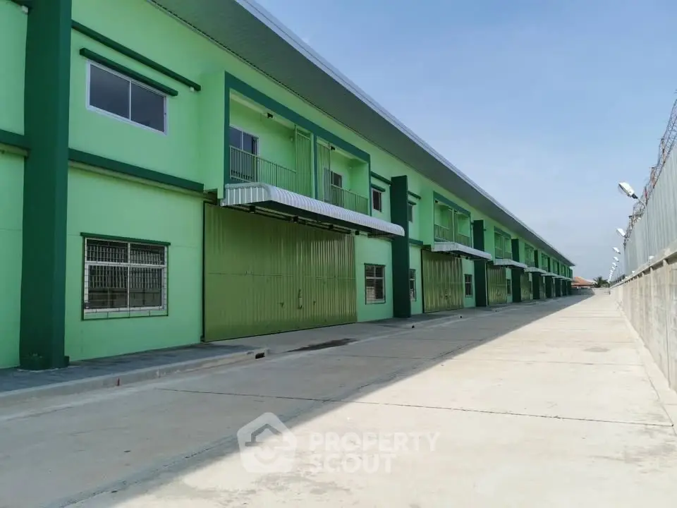 Spacious green industrial warehouse exterior with multiple loading bays and secure fencing.