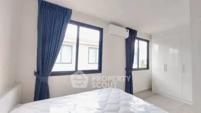 Bright bedroom with large windows, blue curtains, and modern white wardrobe.