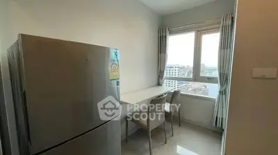 Modern kitchen with fridge and dining area, featuring a city view from the window.