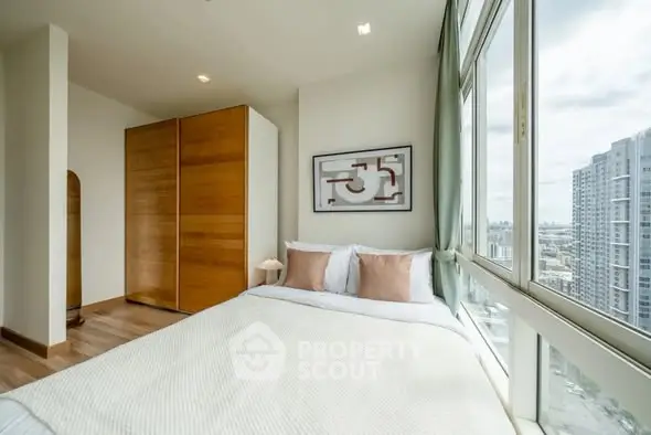 Bright bedroom with large windows offering stunning city views and modern wooden wardrobe.