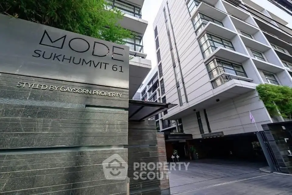 Modern condominium building exterior at Mode Sukhumvit 61 with stylish architecture and lush greenery.