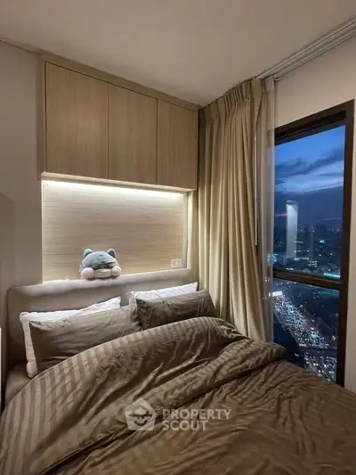 Cozy bedroom with city view, featuring plush bedding and ambient lighting.