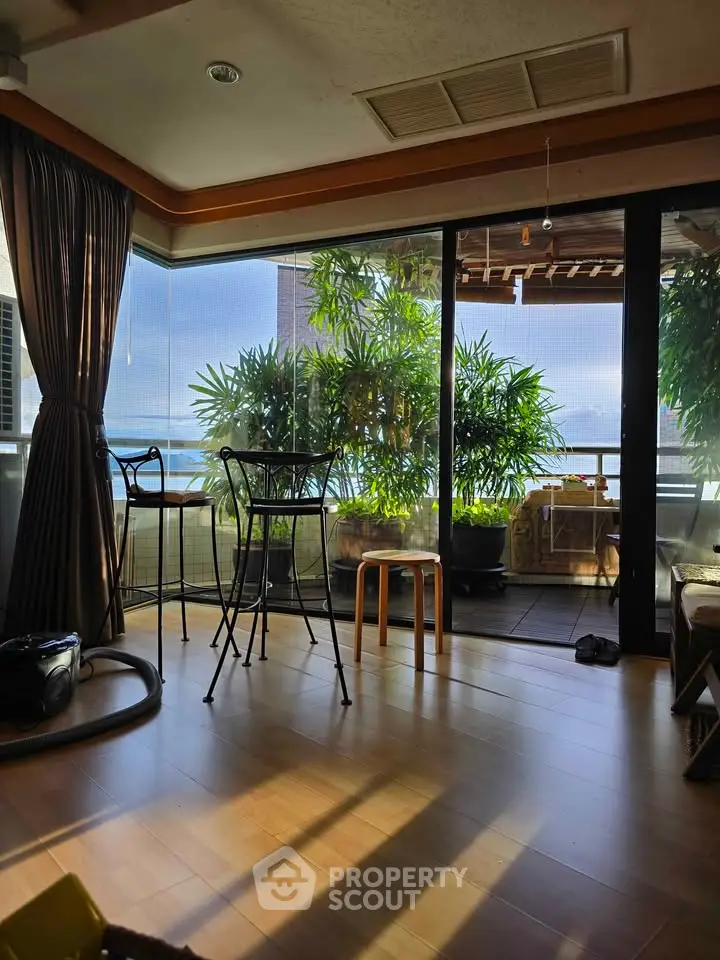 Spacious living room with large windows and balcony view, featuring elegant decor and natural light.