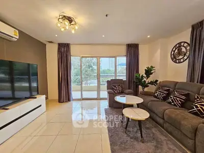 Spacious living room with modern decor and large TV, featuring a balcony view.