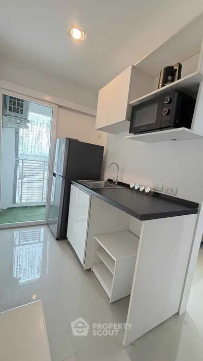 Modern kitchen with sleek appliances and balcony access in a stylish apartment.