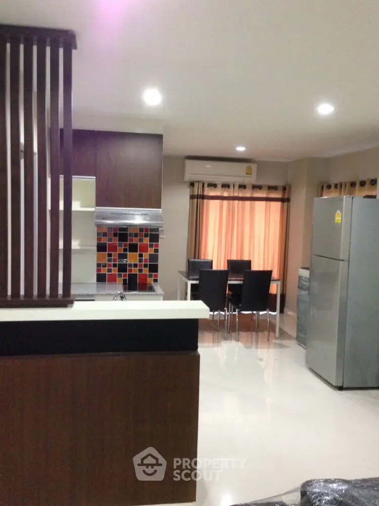 Modern kitchen with dining area, featuring sleek cabinetry and vibrant backsplash.