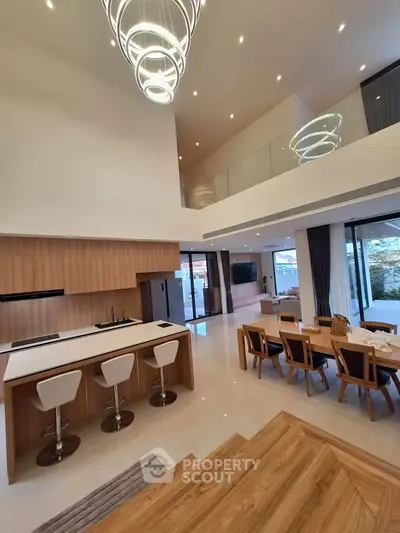Luxurious open-plan living room with modern kitchen and elegant dining area, featuring high ceilings and stylish lighting.