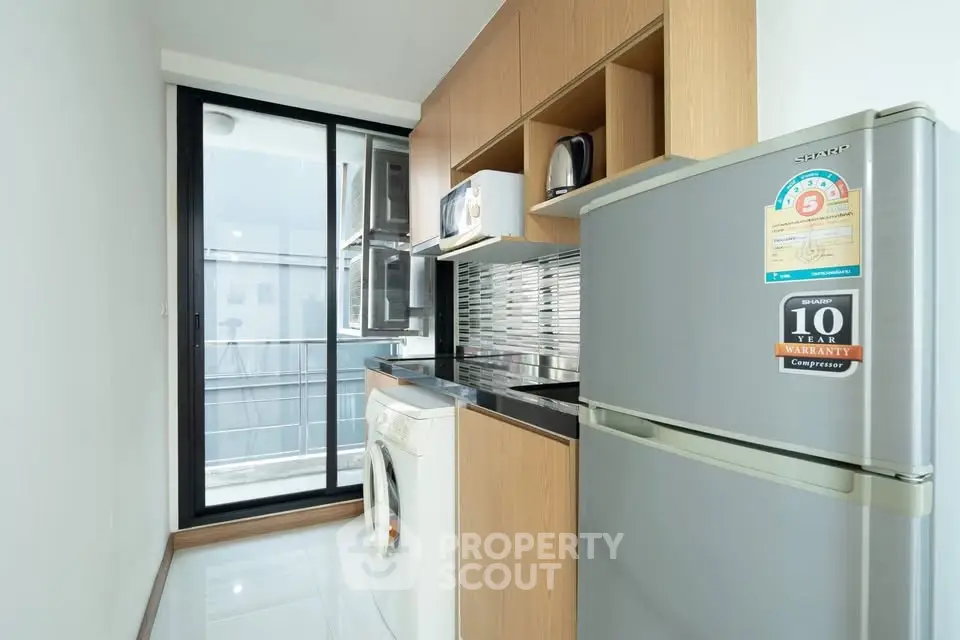 Modern kitchen with sleek appliances and balcony view in urban apartment