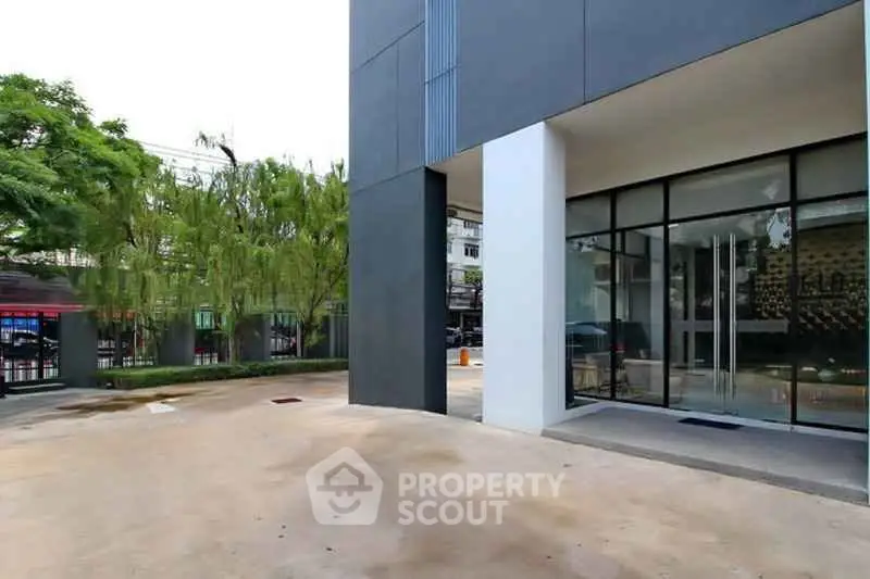 Modern building entrance with sleek glass doors and spacious driveway