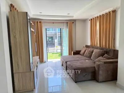 Spacious living room with modern sofa and entertainment unit, opening to a garden view.