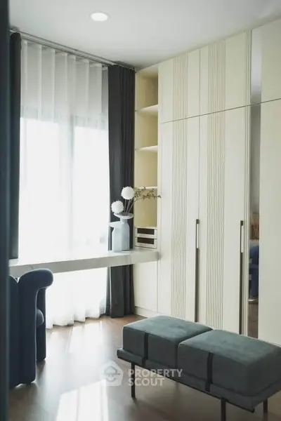 Modern bedroom with elegant decor, featuring a stylish wardrobe and cozy seating area.