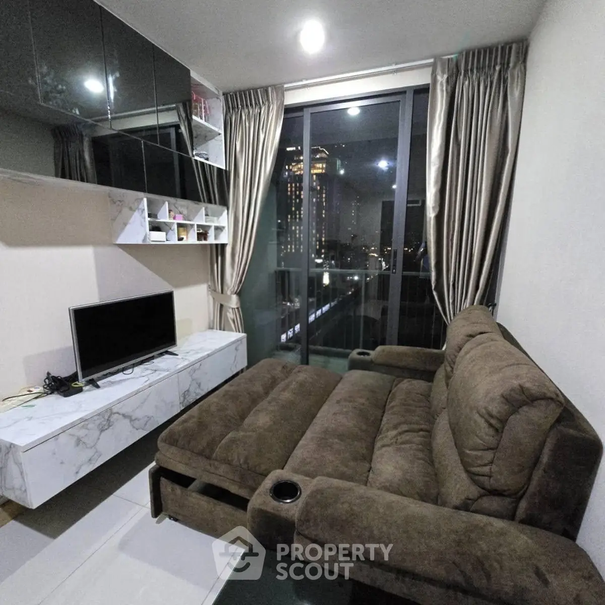 Modern living room with plush sofa and city view balcony in high-rise apartment