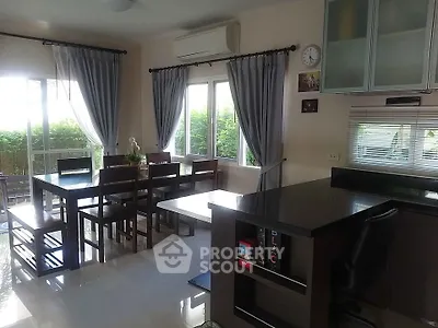 Modern dining area with natural light and garden view, featuring sleek furniture and open layout.