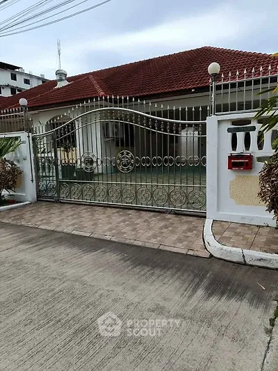 Charming single-story home with red-tiled roof and ornate metal gate in a serene neighborhood.