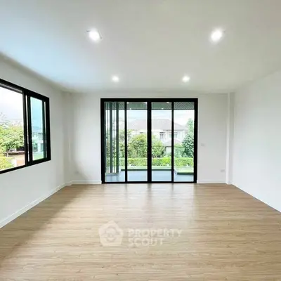 Spacious empty room with large windows and wooden flooring, perfect for customization.
