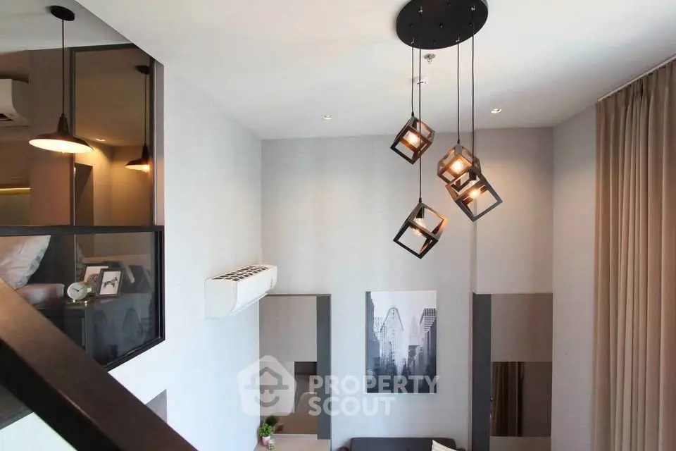 Modern loft-style living room with high ceiling and unique pendant lighting.