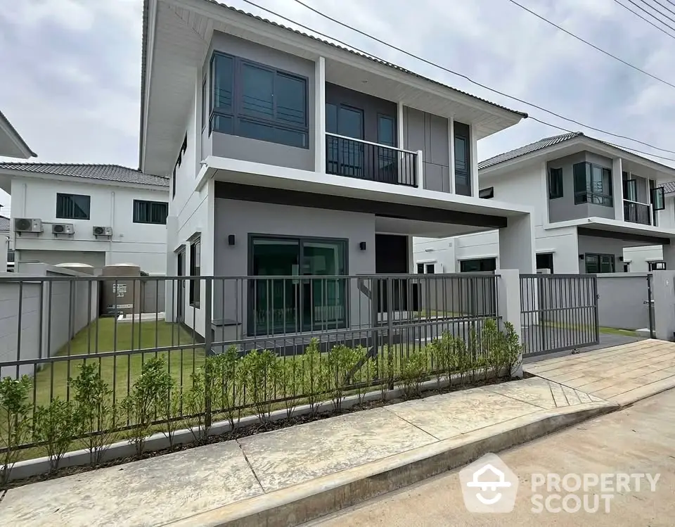 Modern two-story house with sleek design and spacious yard in a suburban neighborhood.