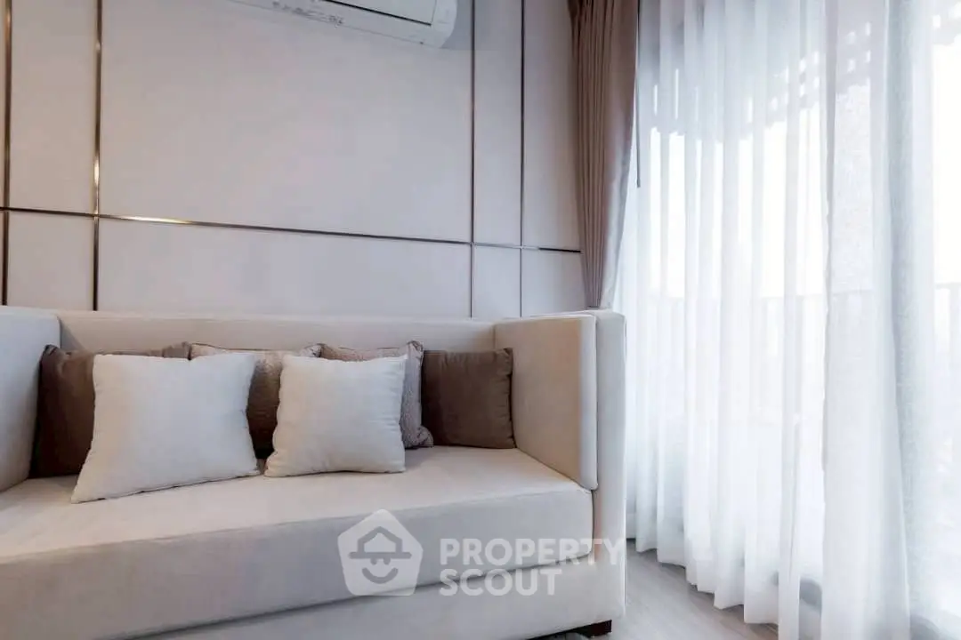 Elegant living room with plush sofa and sheer curtains, perfect for relaxation.