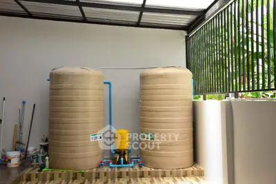Outdoor water storage tanks in a modern residential setting with tiled flooring and green surroundings.