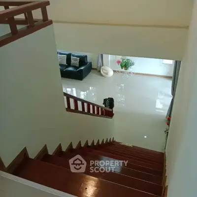 Spacious living room with polished wooden staircase and elegant decor
