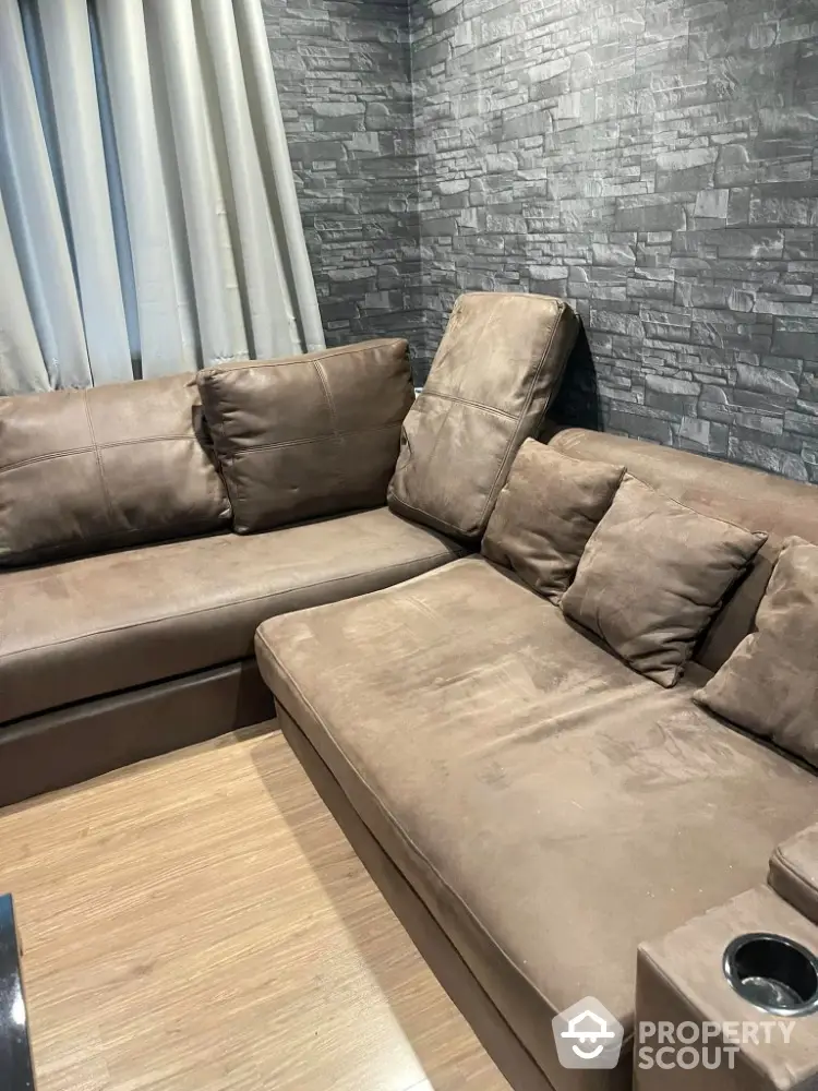 Cozy living room with modern brown sectional sofa and stylish stone accent wall.