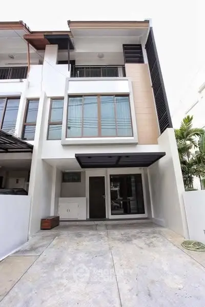 Modern three-story townhouse with large windows and driveway in urban setting.