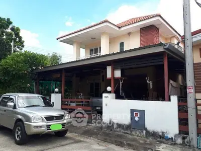 Charming two-story house with carport and lush greenery in a serene neighborhood.