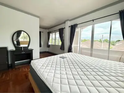 Spacious bedroom with large windows and elegant decor in a modern home.