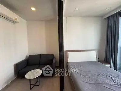 Modern studio apartment with cozy living area and bed, featuring sleek design and natural light.