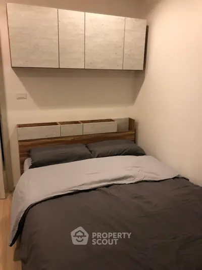 Cozy bedroom with modern wooden bed and overhead storage cabinets, perfect for a restful retreat.