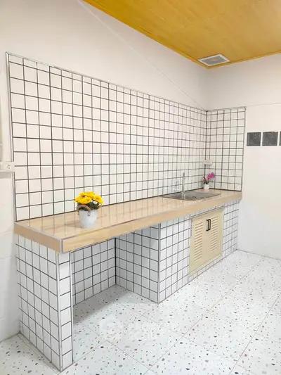 Charming kitchen with tiled walls and countertop, featuring a sleek sink and vibrant decor.