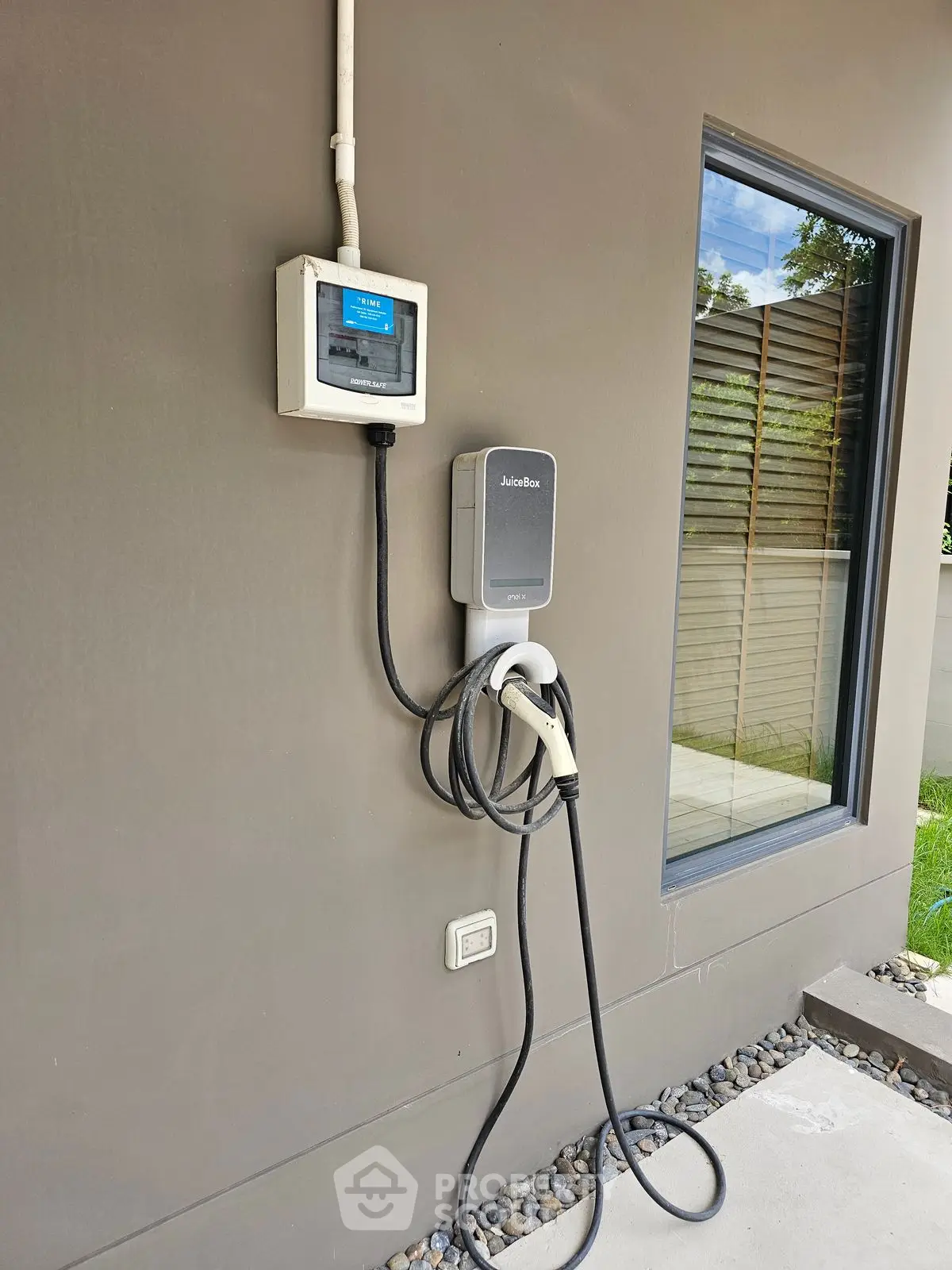 Modern home exterior with electric vehicle charging station installed on wall.