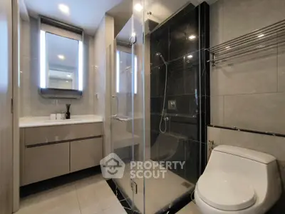 Modern bathroom with glass shower and sleek vanity in luxury apartment.