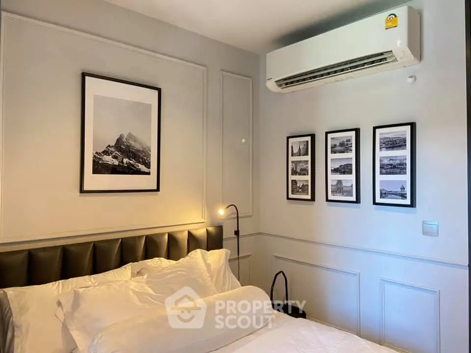 Modern bedroom with stylish decor and air conditioning unit, featuring elegant wall art and cozy bedding.