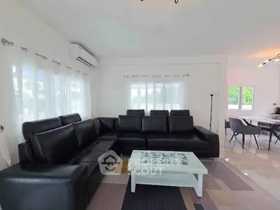 Spacious modern living room with black leather sectional sofa and stylish coffee table.
