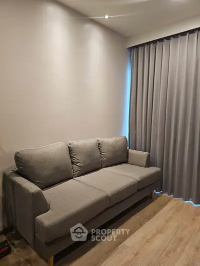Modern living room with sleek gray sofa and elegant curtains, perfect for cozy relaxation.
