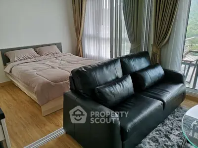 Modern studio apartment with cozy bed and stylish black leather sofa