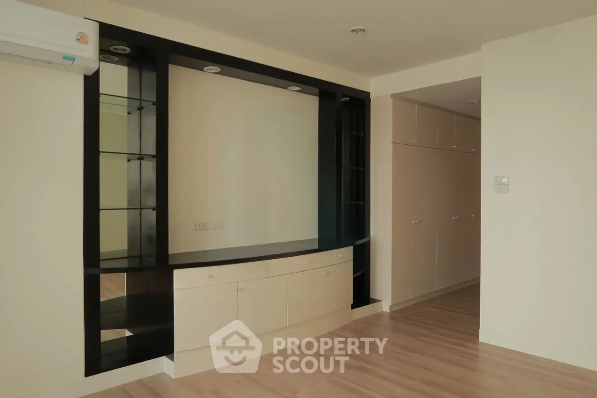 Spacious modern living room with built-in storage and sleek wooden flooring.