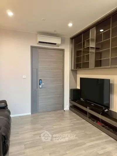 Modern living room with sleek TV setup and air conditioning, featuring stylish wooden flooring and built-in storage.