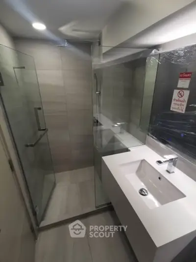 Modern bathroom with sleek glass shower and stylish vanity in contemporary apartment.